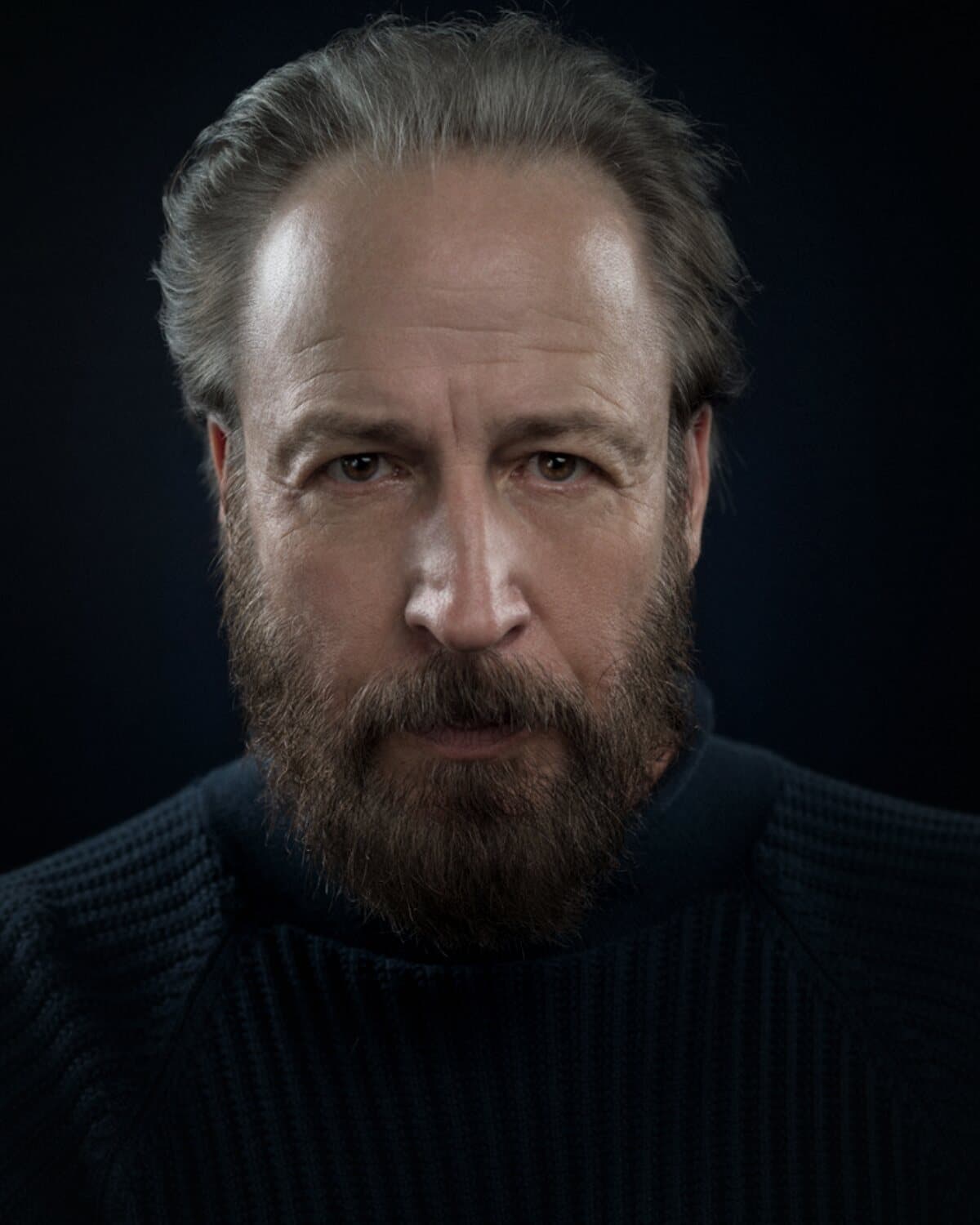 Elvis Winterbottom headshot, dark sweater, moody light